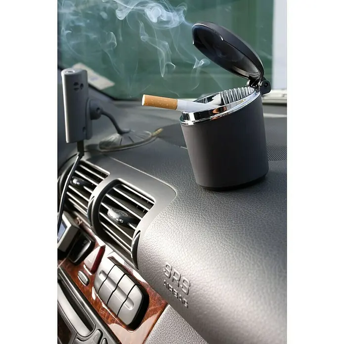 Cenicero para coche - Plástico, Negro - Foto del interior de un coche con un cenicero que contiene un cigarrillo encendido.