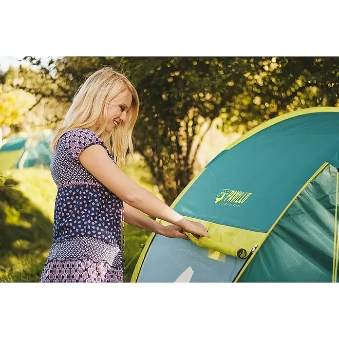 Bestway Pavillo Wurfzelt - L x B x H: 235 x 145 x 100 cm, Türkis, Max. Personenzahl: 2 - Eine Frau lächelt beim Öffnen eines grün-gelben Pavillo-Campingzeltes im Freien.