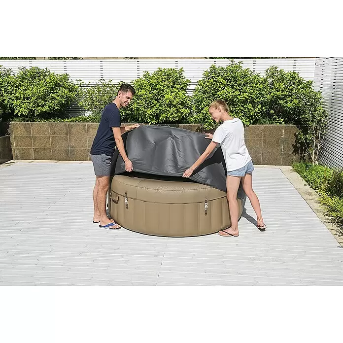 Bestway Lay-Z-Spa Pool-Abdeckplane - Passend für: Runde Whirlpools bis Ø x H: 196 x 71 cm - Zwei Personen decken einen beigen aufblasbaren Whirlpool mit einer grauen Abdeckung im Freien zu.