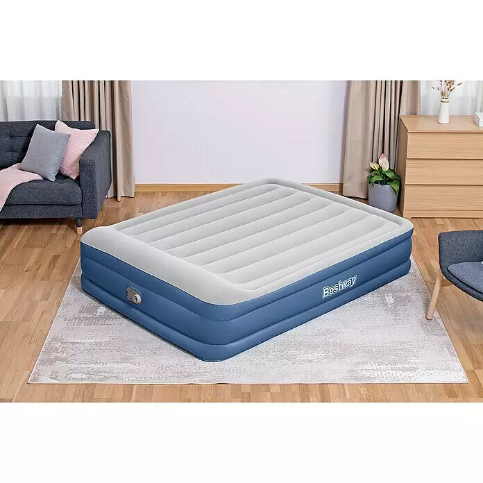Bestway Luftbett Vento - L x B x H: 203 x 152 x 46 cm, Integrierte Luftpumpe - Eine aufgeblasene Bestway Luftmatratze mit blauem Unterteil und weißer, gerippter Oberseite, mit integrierter Pumpe, auf einem Teppich in einem Raum.