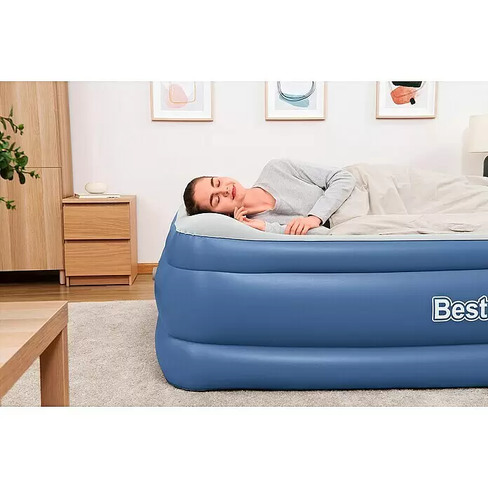 Bestway Luftbett Vento - L x B x H: 203 x 152 x 61 cm, Integrierte Luftpumpe - Blaues aufblasbares Luftbett mit einer bequem darauf schlafenden Frau in einem hellen Raum.