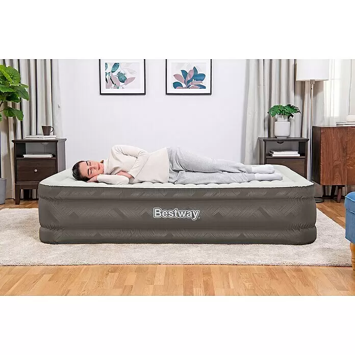 Bestway Luftbett Fortech - L x B x H: 203 x 152 x 46 cm, Integrierte Luftpumpe - Eine Frau schläft bequem auf einer grauen aufblasbaren Bestway Luftmatratze im Schlafzimmer.