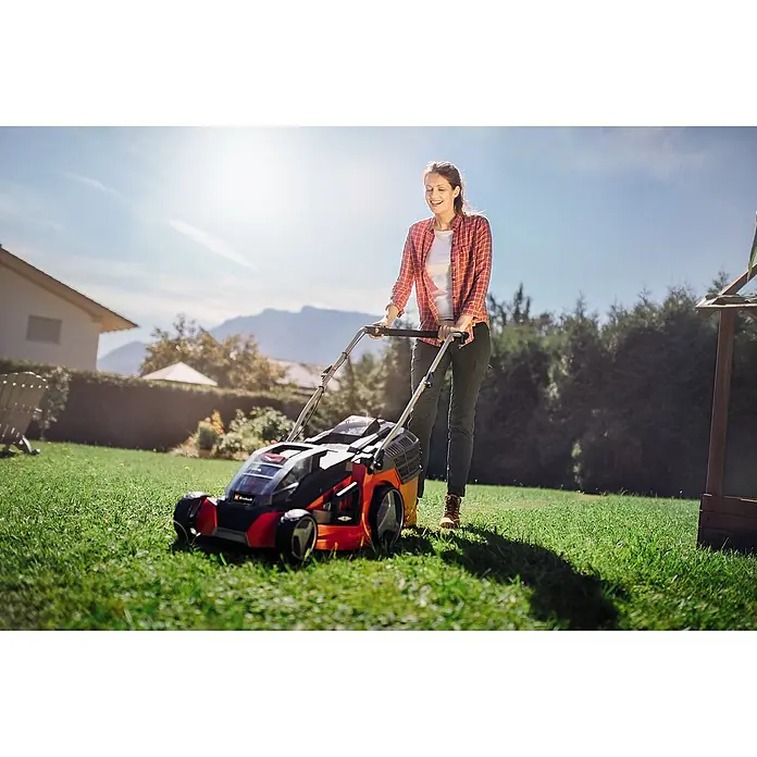 Einhell PXC 18V Cortacésped de batería GE-CM 43 Li M Kit - 18 V, 2 baterías, 4 Ah, Ancho de corte: 43 cm - Una mujer usa una cortadora de césped inalámbrica Einhell en el jardín para cortar el césped.