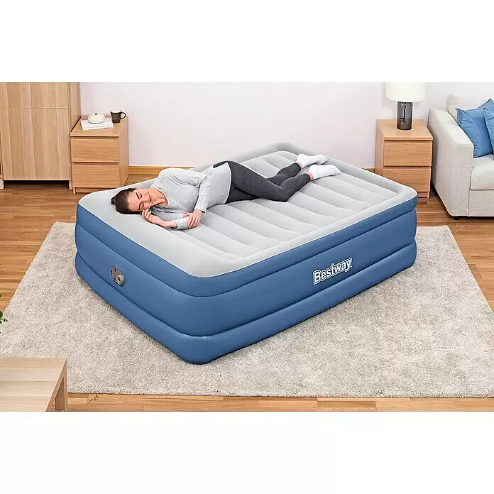 Bestway Luftbett Vento - L x B x H: 203 x 152 x 61 cm, Integrierte Luftpumpe - Blaues und graues Bestway aufblasbares Luftbett mit einer Frau, die darauf in einem Raum ruht.