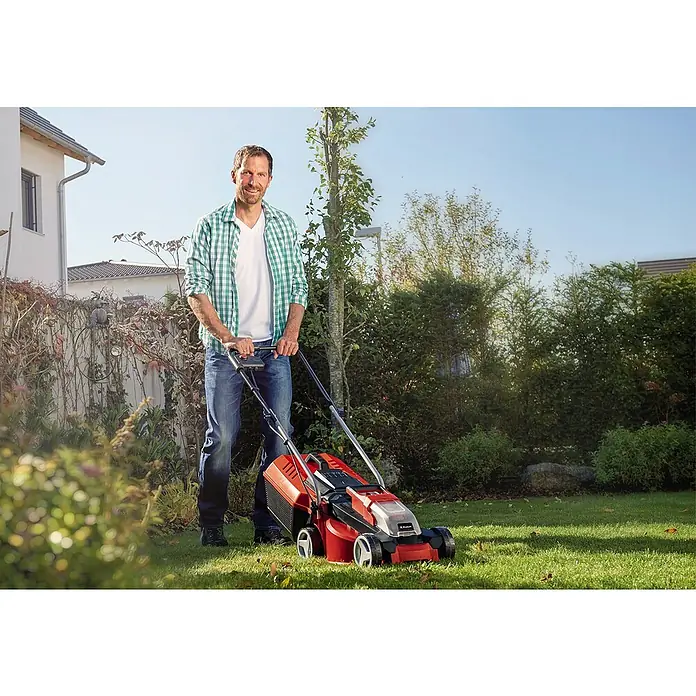 Einhell PXC 18V Cortacésped de batería GE-CM 18/30 Li - 18 V, Iones de litio, 3 Ah, 1 batería, Ancho de corte: 30 cm - Un hombre corta el césped con un cortacésped Einhell rojo en el jardín. El dispositivo es robusto e ideal para el cuidado del césped.