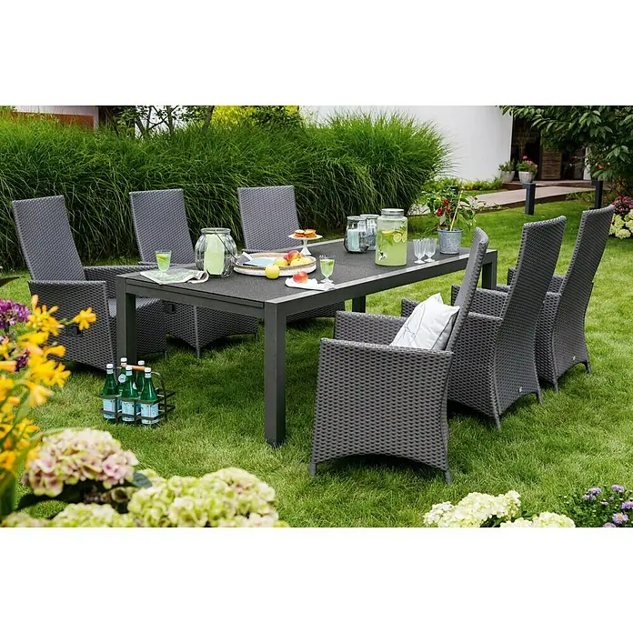 Sunfun Maja Mesa de jardín XL - L x An x Al: 280 x 100 x 75 cm, Aluminio, vidrio, Rectangular, Antracita, Extensible - Un juego de comedor gris para exteriores con mesa y sillas, rodeado de exuberante vegetación, ideal para reuniones al aire libre.
