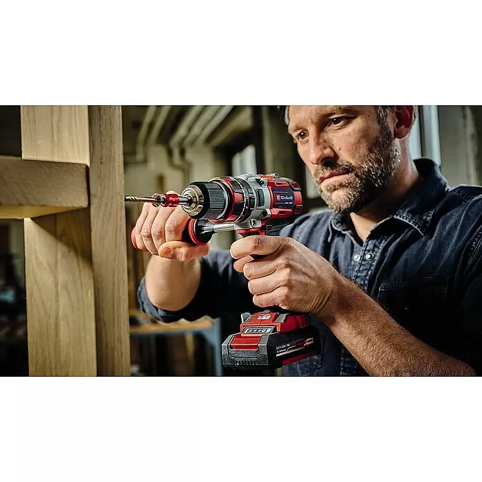 Einhell Professional Power X-Change 18V Akku-Schlagbohrschrauber TP-CD 18 Li-i BL - 18 V, 2 Akkus, 60 Nm - Ein Mann verwendet einen rot-schwarzen Akkubohrschrauber, um eine Schraube in eine Holzkonstruktion zu bohren.