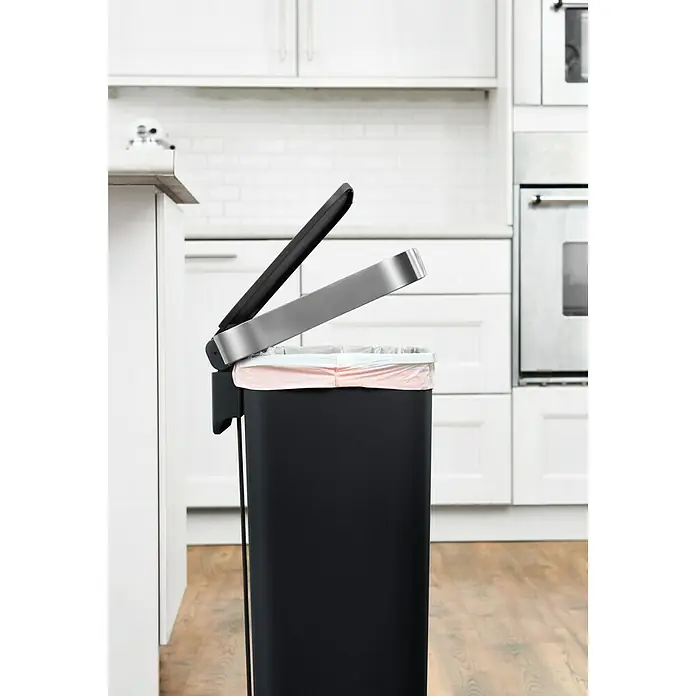 Vepa Bins Treteimer Hana - 45 l, Kunststoff, Schwarz - Ein schwarzer Mülleimer mit offenem Deckel und einem rosa Müllbeutel steht in einer hellen Küche, der Fokus liegt auf dem Mülleimer.