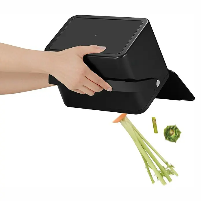 Vepa Bins Standard Mülleimer Foodwaste Caddy - 4 l, Kunststoff, Schwarz - Eine Person leert einen schwarzen Komposteimer, wodurch Gemüsereste herausfallen.