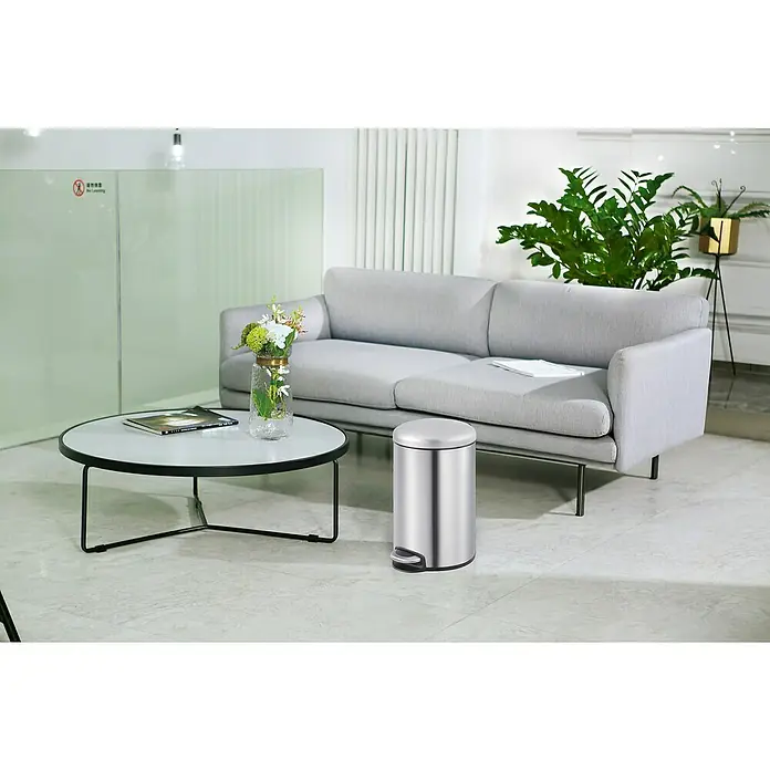 Vepa Bins Treteimer Maggey - 20 l, Edelstahl, Mattsilber - Eine elegante Szene mit einer modernen Couch, einem stilvollen Tisch und einem schlanken, silbernen Mülleimer, die ein harmonisches Interieur schaffen.