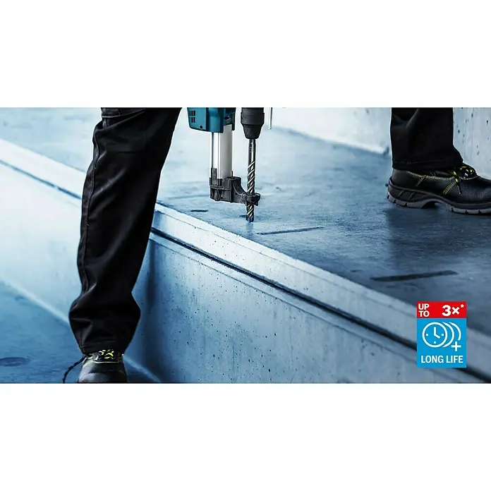 Bosch Expert Beton- & Steinbohrer SDS Plus-7X - 1 Stk., Durchmesser Bohrer: 15 mm, 100 mm - Nahaufnahme einer Bohrmaschine, die in eine Betonoberfläche bohrt. Zu sehen sind auch Arbeitshose und Sicherheitsschuhe.