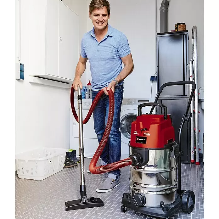 Einhell PXC 18V Aspirador en seco y húmedo de batería TE-VC 36/30 Li S-Solo - 18 V, Sin batería, Volumen de recipiente: 30 l - Un hombre usa una aspiradora en seco y húmedo roja y plateada para limpiar un suelo.