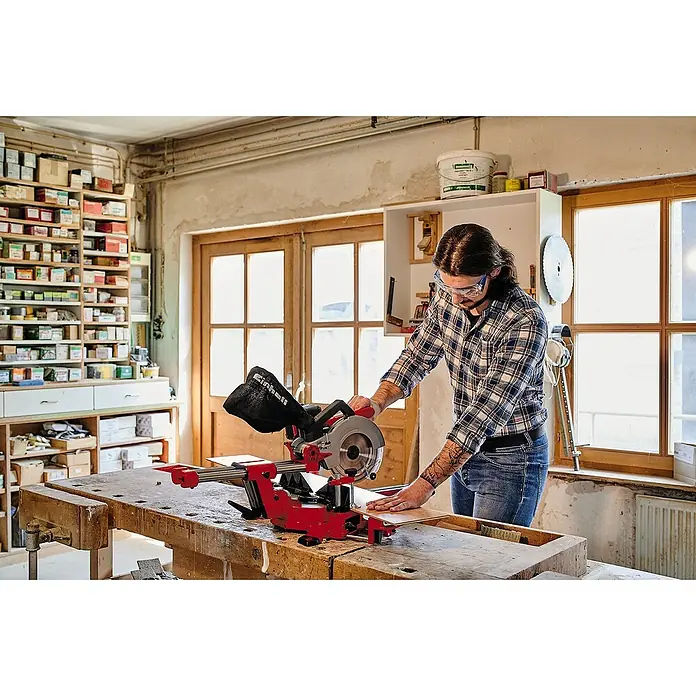 Einhell Power X-Change 18V Akku-Kapp- & Gehrungssäge TE-SM 36/210 Li-Solo - 36 V, Ohne Akku, 3.800 U/min - Eine Einhell Kapp- und Gehrungssäge beim Schneiden von Holz in einer Werkstatt, mit einem Mann in kariertem Hemd und Schutzbrille.