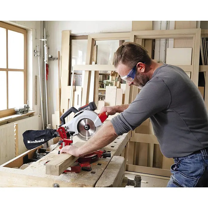 Einhell Power X-Change 18V Akku-Kapp- & Gehrungssäge TE-MS 18-210 Li-Solo - 18 V, Ohne Akku, Durchmesser Sägeblatt: 210 mm, Leerlaufdrehzahl: 3.000 U/min - Mann arbeitet mit einer Einhell Kapp- und Gehrungssäge an einem Holzstück, trägt dabei Schutzbrille und Gehörschutz.