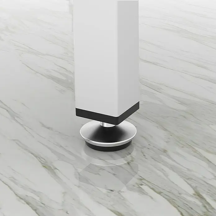 Rei Tornillo regulable - Cromo, 4 ud. - Primer plano de una pata de mesa blanca y moderna con un pie plateado sobre un suelo de mármol. El diseño es elegante y minimalista.