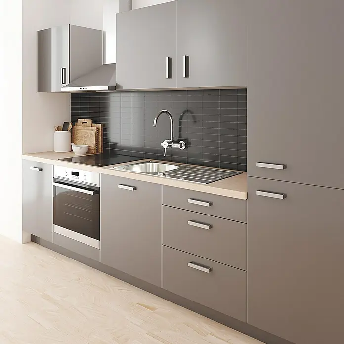 Grohe Concetto Spültischarmatur - Chrom, Glänzend, Wandmontage - Eine moderne Küche mit grauen Schränken, einer Spüle und einem Kochfeld unter einer Dunstabzugshaube. Helle Holzböden ergänzen das Erscheinungsbild.