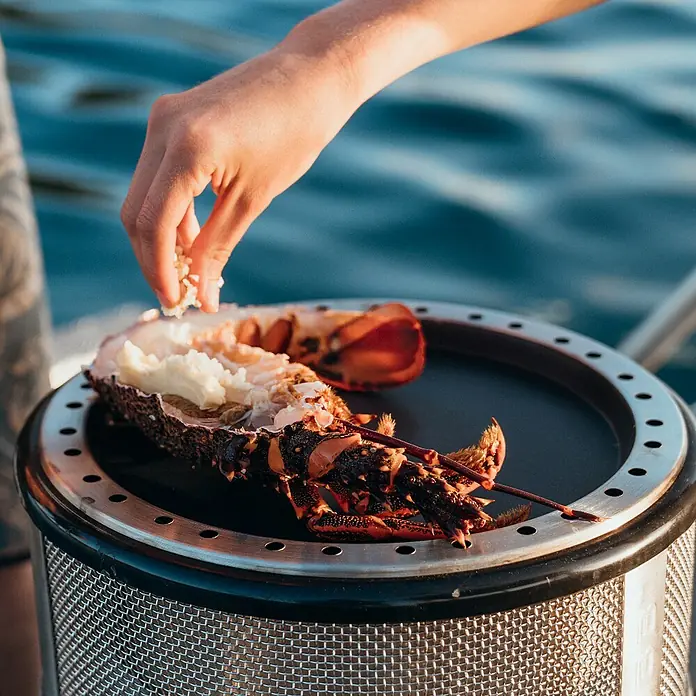 Cobb Grillpfanne - Durchmesser: 30,4 cm, Höhe: 1,9 cm - Vorbereitung eines halben Hummers auf einem runden Grill mit Meeresblick, garniert mit Zutaten.