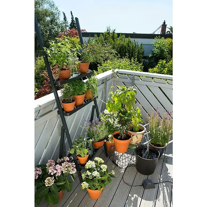Gardena Micro-Drip Urlaubsbewässerung - Passend für: Für bis zu 36 Topfpflanzen - Eine Nahaufnahme eines Balkons mit einer Pflanzenleiter, auf der verschiedene Topfpflanzen stehen, darunter Kräuter und Blumen.