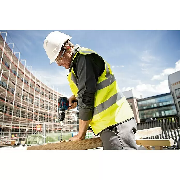 Bosch Professional AMPShare 18V Akku-Schlagbohrschrauber GSB 18V-55 - 18 V, 2 Akkus, 4 Ah, 55 Nm, Inkl. 2 x Akku 4 Ah + Koffer - Ein Mann in Schutzkleidung bohrt mit einem blau-schwarzen Bosch Akku-Bohrschrauber in ein Holzbrett auf einer Baustelle.