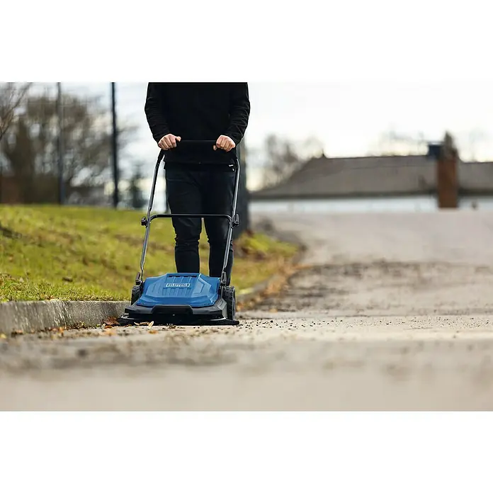 Scheppach Handkehrmaschine S800 - Flächenleistung: 2.600 m²/h, 20 l - Eine Person benutzt eine blaue Scheppach Kehrmaschine, um eine Straße von Laub und Schmutz zu säubern.