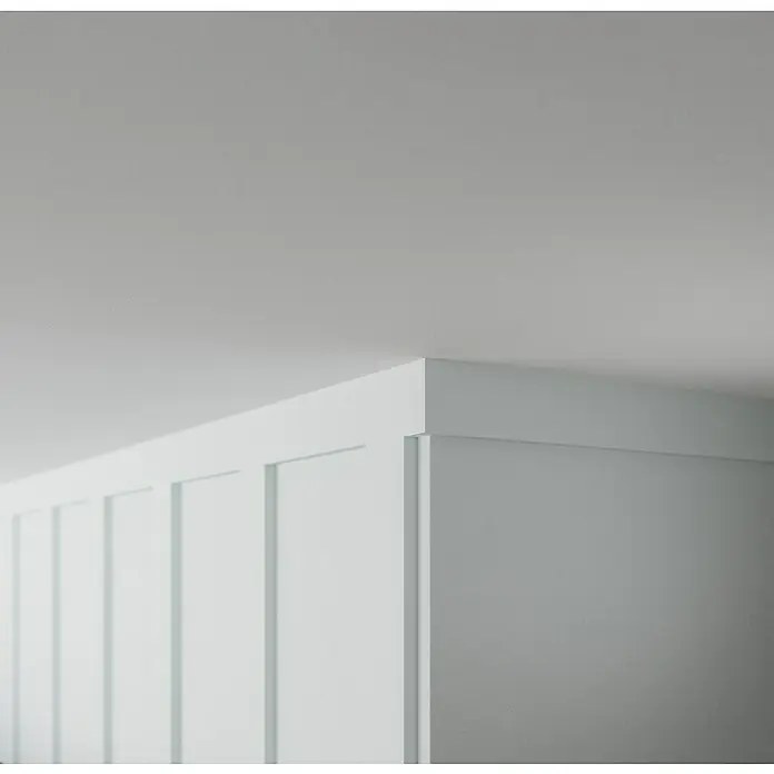 Nmc Decoflair Zierprofil Wandleiste C9 - 2 m x 15 mm x 70 mm, Hochverdichtetes extrudiertes Polymer (HDPS) - Nahaufnahme einer weißen Paneelwand mit einer klaren Linienführung und einer schlichten Ästhetik, die moderne Eleganz ausstrahlt.