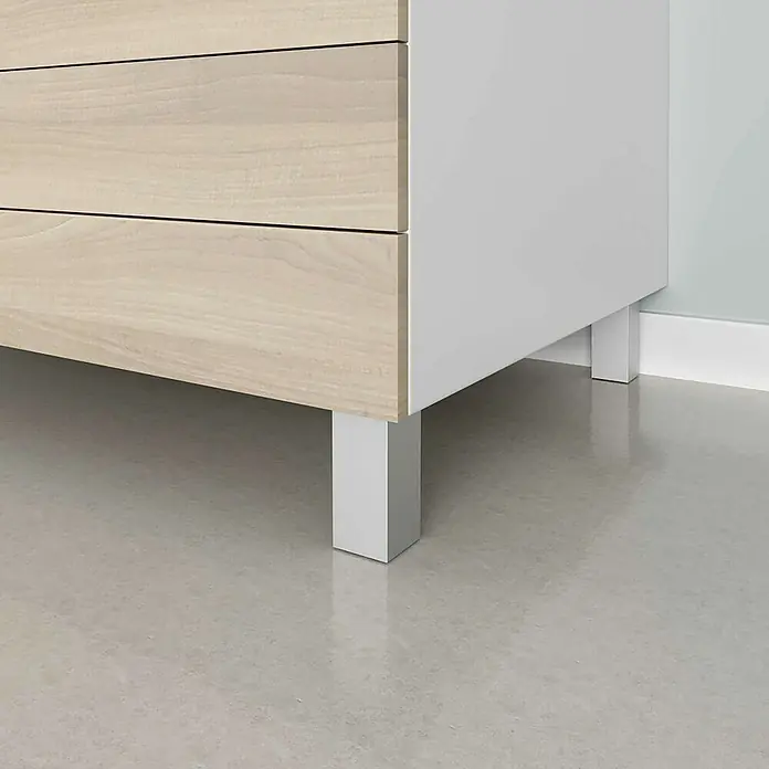 Rei Möbelfuß-Set - L x B x H: 4 x 4 x 10 cm, Aluminium, 4 Stk. - Nahaufnahme eines Kommode mit hellen Holzschubladen und weißen Beinen auf einem glatten, hellen Boden. Die Kommode steht stabil und modern.