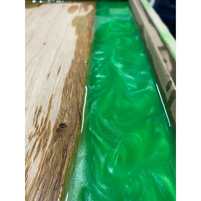 CreativEpoxy Gießharz Resin 50 A+B - 6,75 kg, Passend für: Bis zu 50 mm Schichtstärke - Nahaufnahme eines Holztisches mit einem Fluss aus grünem Epoxidharz, der ein einzigartiges und auffälliges Designelement bildet.