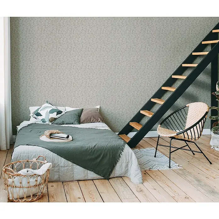 A.S. Création Metropolitan Stories Travel Styles Vliestapete Blätter-Allover II - Beige, Floral, 10,05 x 0,53 m - Schlafzimmer mit einem bequemen Bett, einer dekorativen Leiter und einem stilvollen Korbstuhl, die eine gemütliche und einladende Atmosphäre schaffen.