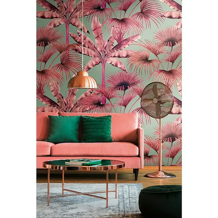 A.S. Création Metropolitan Stories Travel Styles Fototapete Palmen - B x H: 1,59 x 2,8 m, Vlies, Pink - Wohnzimmer mit rosa Sofa, grünen Kissen, Kupfertisch, Lampe und Ventilator vor Palmentapete.