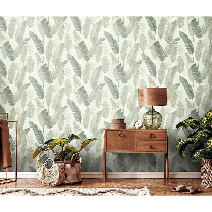 A.S. Création Metropolitan Stories Travel Styles Vliestapete - Creme/Grün, Floral, 10,05 x 0,53 m - Dekorativer Innenraum mit botanischer Tapete, Nachttisch aus Holz mit Lampe, Pflanzen und Teppich für eine gemütliche Atmosphäre.