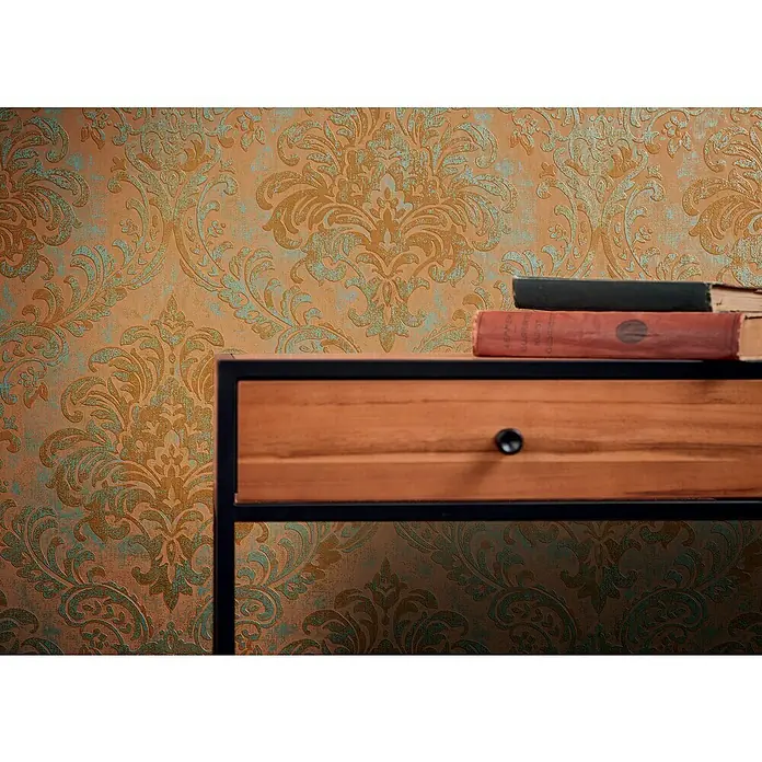 A.S. Création Metropolitan Stories Travel Styles Vliestapete Damask - Orange, Ornament, 10,05 x 0,53 m - Detailaufnahme einer stilvollen Kommode mit Bücherstapel vor einer verzierten Tapete.