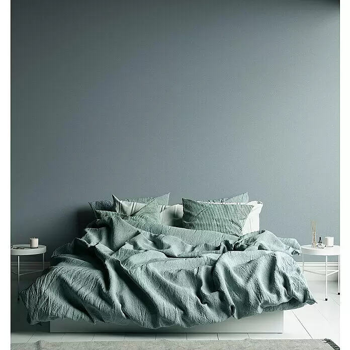 A.S. Création Metropolitan Stories Travel Styles Vliestapete - Blau/Grün, Uni, 10,05 x 0,53 m - Ein Bett mit weicher, zerknitterter mintgrüner Leinenbettwäsche und gestreiften Kissen in einem modernen Schlafzimmer.
