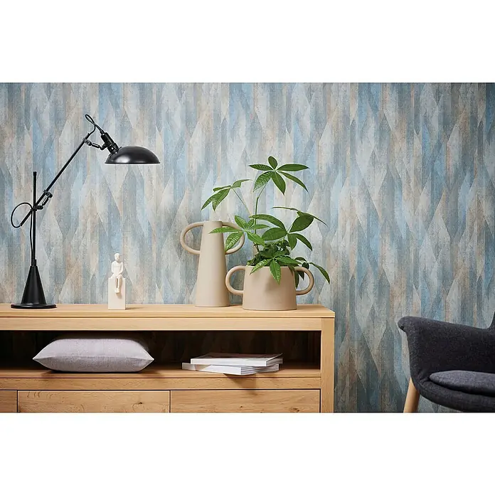 A.S. Création Metropolitan Stories Travel Styles Vliestapete Vintage - Blau/Creme, Grafisch, 10,05 x 0,53 m - Elegantes Interieur mit stilvoller Kommode, Lampe und dekorativen Elementen vor einer gemusterten Wand.