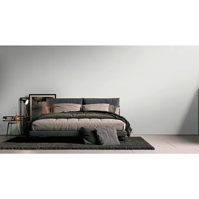 A.S. Création Metropolitan Stories Travel Styles Vliestapete - Melange-Weiß, Uni, 10,05 x 0,53 m - Elegantes Schlafzimmer mit einem modernen grauen Bett, das mit weichen Kissen und einer dunklen Decke für Komfort und Stil sorgt.