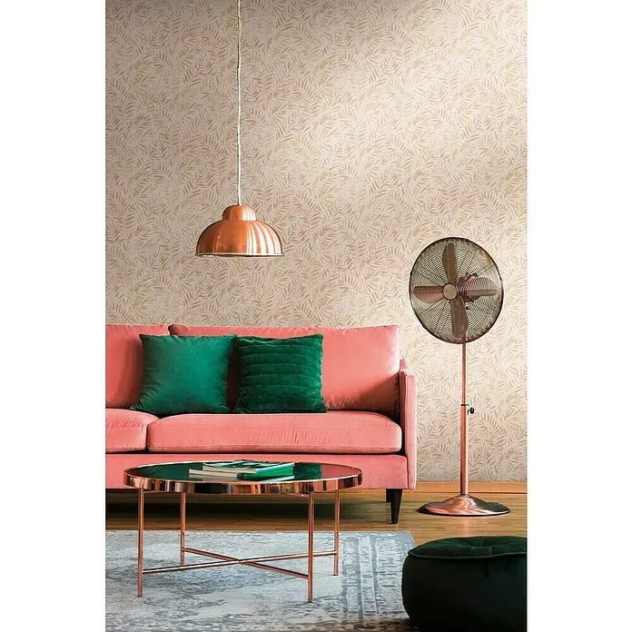 A.S. Création Metropolitan Stories Travel Styles Vliestapete Blätter-Allover I - Rosè/Gold, Floral, 10,05 x 0,53 m - Ein gemütliches Wohnzimmer mit einem rosa Sofa, grünen Kissen, einem kupferfarbenen Tisch und einer passenden Stehlampe. Die Tapete hat ein dezentes Blättermuster.