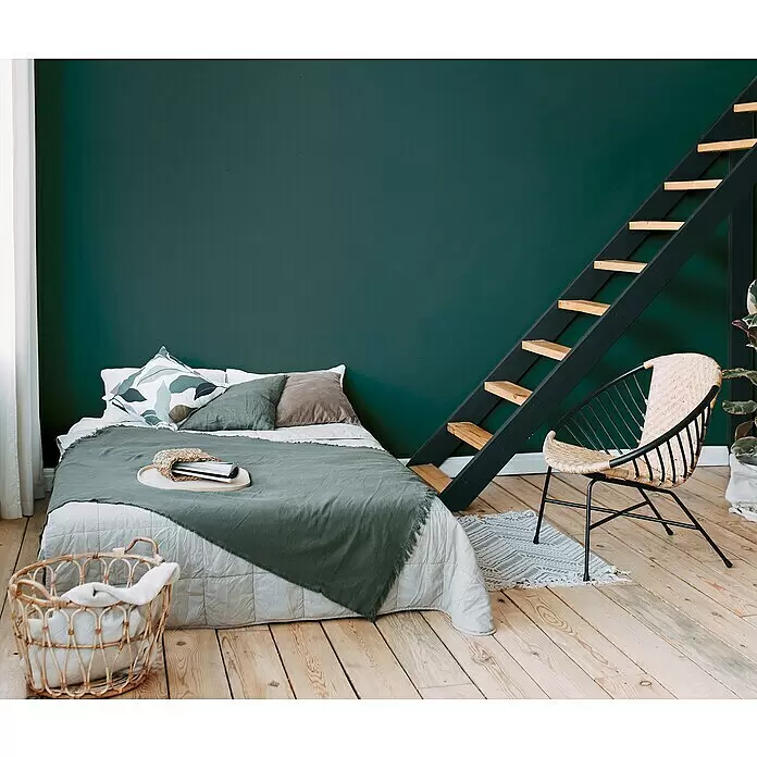 A.S. Création Metropolitan Stories Travel Styles Vliestapete - Blaugrün, Uni, 10,05 x 0,53 m - Ein modernes Schlafzimmer mit einem Bett, einem Korbstuhl und einer schwarzen Leiter mit Holzstufen.