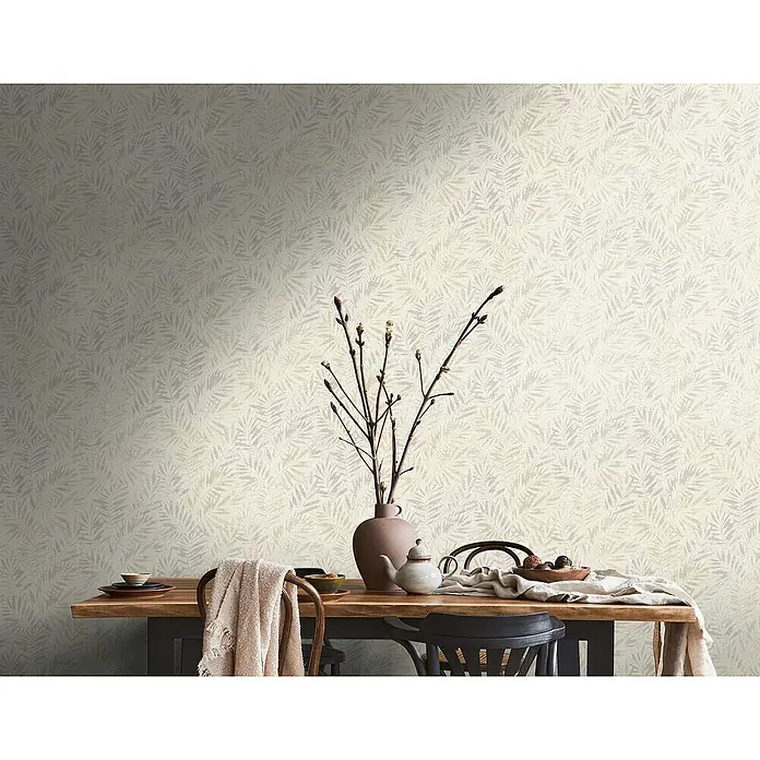 A.S. Création Metropolitan Stories Travel Styles Vliestapete Blätter-Allover ICreme, Floral, 10,05 x 0,53 m - Eine Nahaufnahme von einer Wand mit einer Blattmuster-Tapete in Beige- und Grautönen, die eine subtile und elegante Textur verleiht.