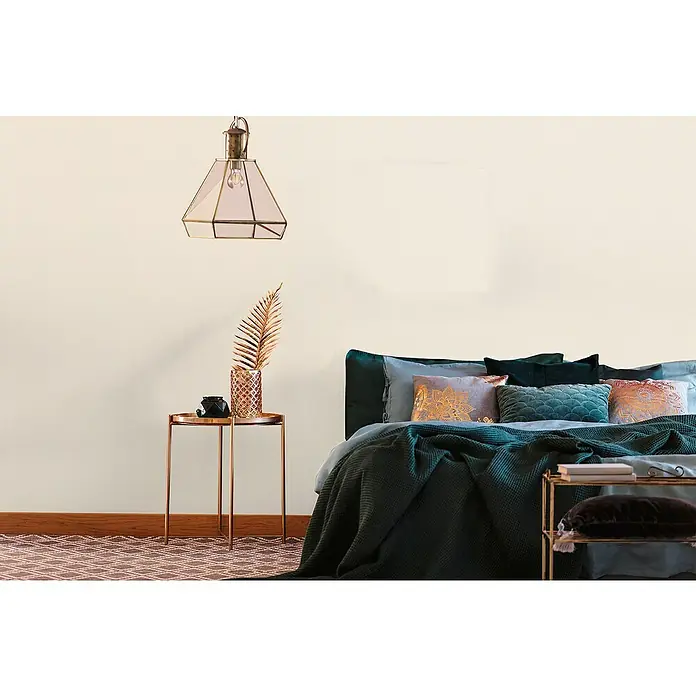 A.S. Création Metropolitan Stories Travel Styles Vliestapete - Melange-Creme, Uni, 10,05 x 0,53 m - Ein stilvolles Schlafzimmer mit einem Bett mit grünen und blauen Kissen und Decken, einem Beistelltisch und einer dekorativen Lampe.