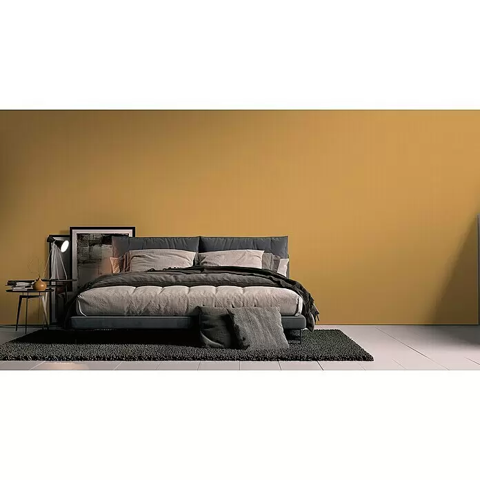 A.S. Création Metropolitan Stories Travel Styles Vliestapete - Ocker, Uni, 10,05 x 0,53 m - Modernes graues Polsterbett mit heller und dunkler Bettwäsche, auf einem dunklen Teppich im Schlafzimmer.