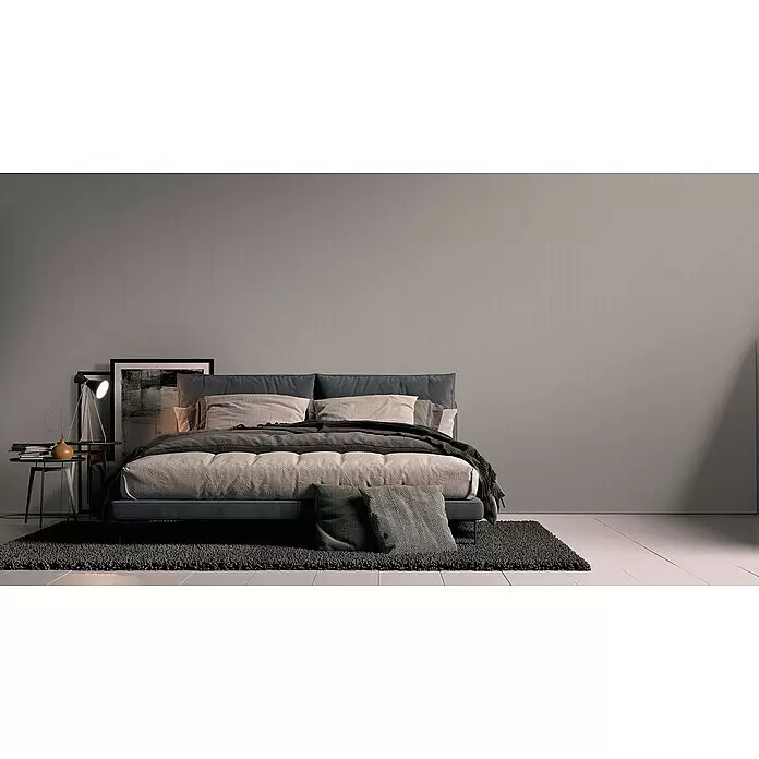 A.S. Création Metropolitan Stories Travel Styles Vliestapete - Taupe, Uni, 10,05 x 0,53 m - Dunkelgraues Polsterbett mit heller Bettwäsche und Zierkissen in modernem Schlafzimmer.