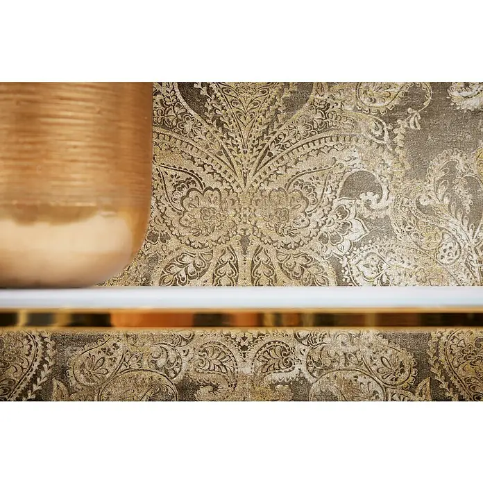 A.S. Création Metropolitan Stories Travel Styles Vliestapete DamaskGold/Braun, Ornament, 10,05 x 0,53 m - Nahaufnahme eines dekorierten goldenen Gefäßes auf einem Regal vor einer verzierten Tapete, die Eleganz und Stil ausstrahlt.