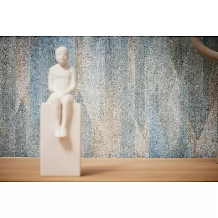 A.S. Création Metropolitan Stories Travel Styles Vliestapete Vintage - Blau/Creme, Grafisch, 10,05 x 0,53 m - Weiße Figur sitzt auf einem Podest vor einer blau-braun gemusterten Wand.