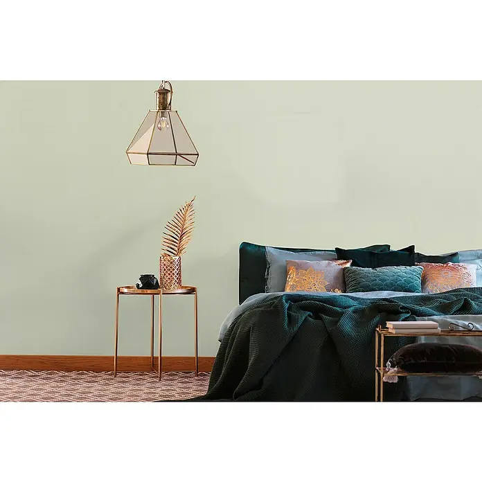 A.S. Création Metropolitan Stories Travel Styles Vliestapete - Sandgrün, Uni, 10,05 x 0,53 m - Schlafzimmer mit dekorativem Nachttisch, goldener Lampe und gemütlichem Bett mit Kissen und Decken.
