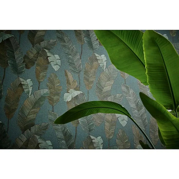 A.S. Création Metropolitan Stories Travel Styles Vliestapete - Blau/Gold, Floral, 10,05 x 0,53 m - Nahaufnahme einer eleganten Wandtapete mit einem faszinierenden Blattmuster und einem Hauch von tropischen Grünpflanzen im Vordergrund.