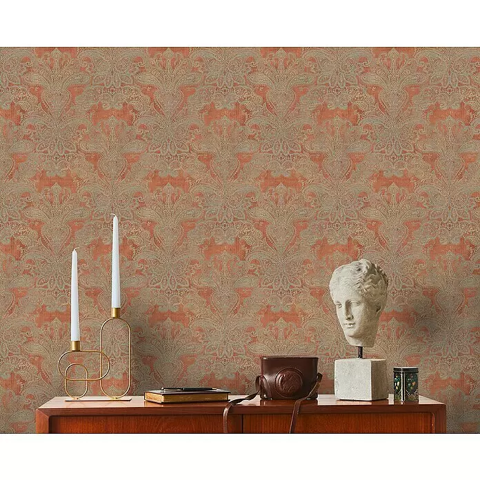 A.S. Création Metropolitan Stories Travel Styles Vliestapete Damask - Orange/Blau, Ornament, 10,05 x 0,53 m - Terrakotta- und grau-gemusterte Paisleymuster-Tapete bedeckt eine Wand hinter einem Holzschrank mit Deko.