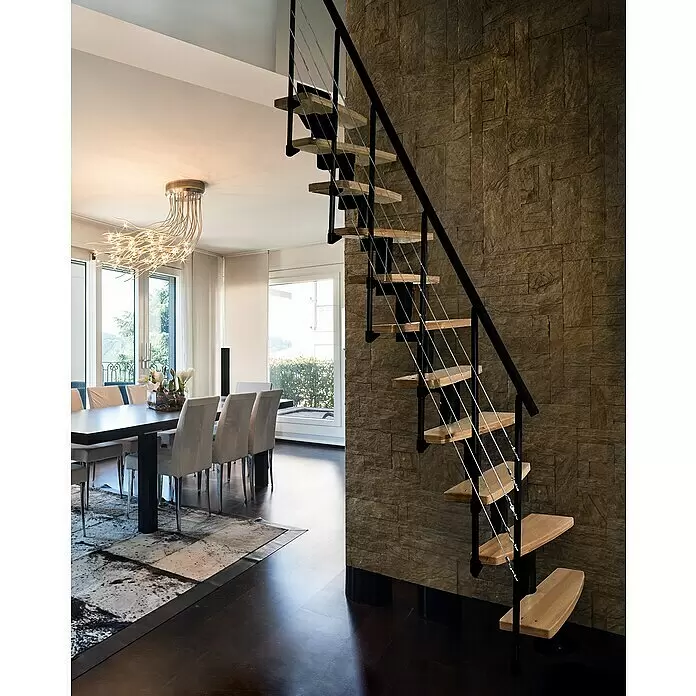 Atrium Raumspartreppe Mini Plus Linco - Farbton Metall: RAL 9005, Breite: 60 cm, Buche, Geschosshöhe: 222 cm - 300 cm - Moderne freitragende Treppe mit hellen Holzstufen, schwarzem Metallrahmen und Stahlseilgeländer, an einer strukturierten Steinwand.