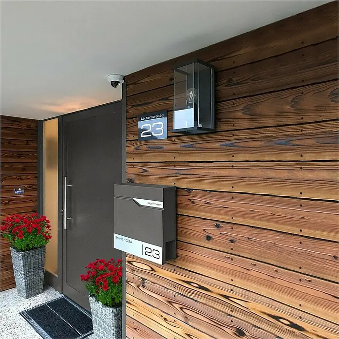 Metzler Wandbriefkasten Siebert - L x B x H: 10,5 x 37 x 37 cm, Eisenglimmer, Stahl, Zeitungsfach - Elegantes Haus mit grauer Tür, Briefkasten und Holzfassade. Nummer 23 ist gut sichtbar.