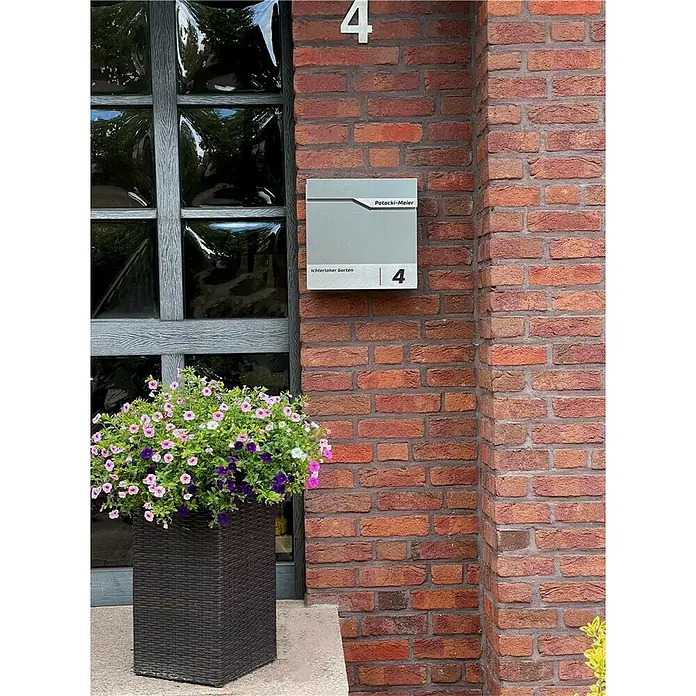 Metzler Wandbriefkasten SiebertL x B x H: 10,5 x 37 x 37 cm, Grau-Aluminium, Stahl, Zeitungsfach - Hausnummer 4 und ein grauer Briefkasten mit der Aufschrift "Potacki-Meier" an einer Backsteinmauer.