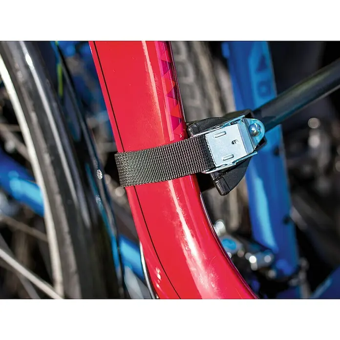 Eufab Portabicicletas Crow + - Apto para: 2 bicicletas, Capacidad de carga: 50 kg - Primer plano de un portabicicletas con una correa que asegura un cuadro de bicicleta rojo, centrado en el mecanismo de fijación.
