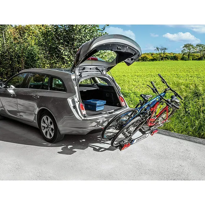 Eufab Portabicicletas Crow + - Apto para: 2 bicicletas, Capacidad de carga: 50 kg - Vista trasera de un coche familiar plateado con el portón trasero abierto y un portabicicletas con dos bicicletas acoplado.